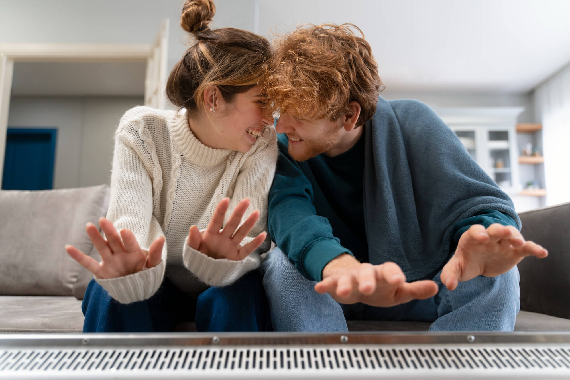 Una coppia si riscalda le mani su un termosifone